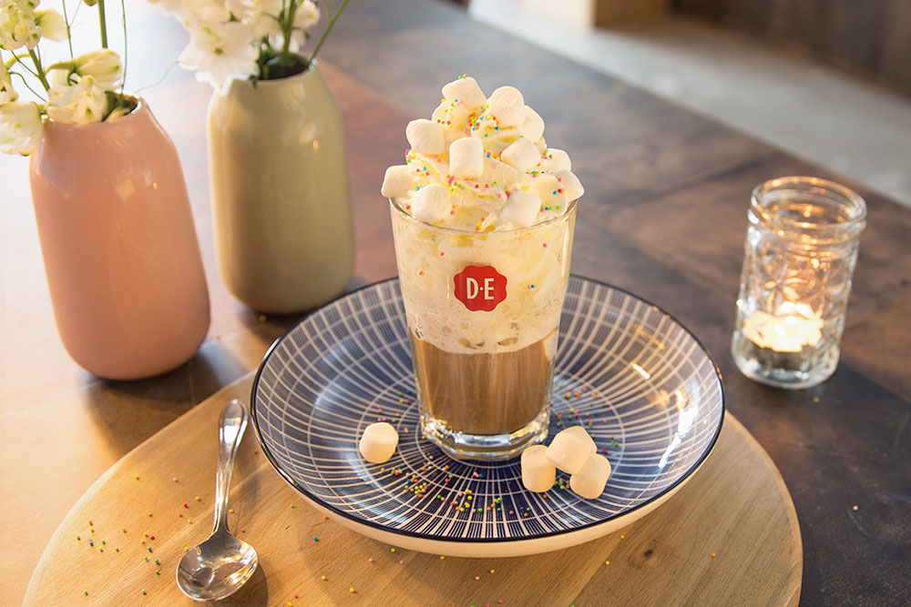 Ijskoffie Party latte op een bord met marshmallows en spikkels.