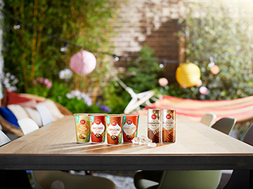 Verschillende Douwe Egberts producten, zoals ijskoffie, op een tuintafel.