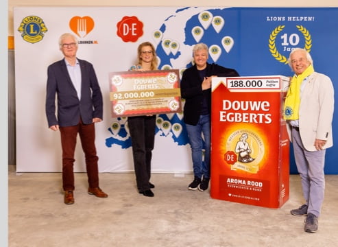 Different people standing next to a cheque and a giant package of Douwe Egberts Aroma Rood Coffee